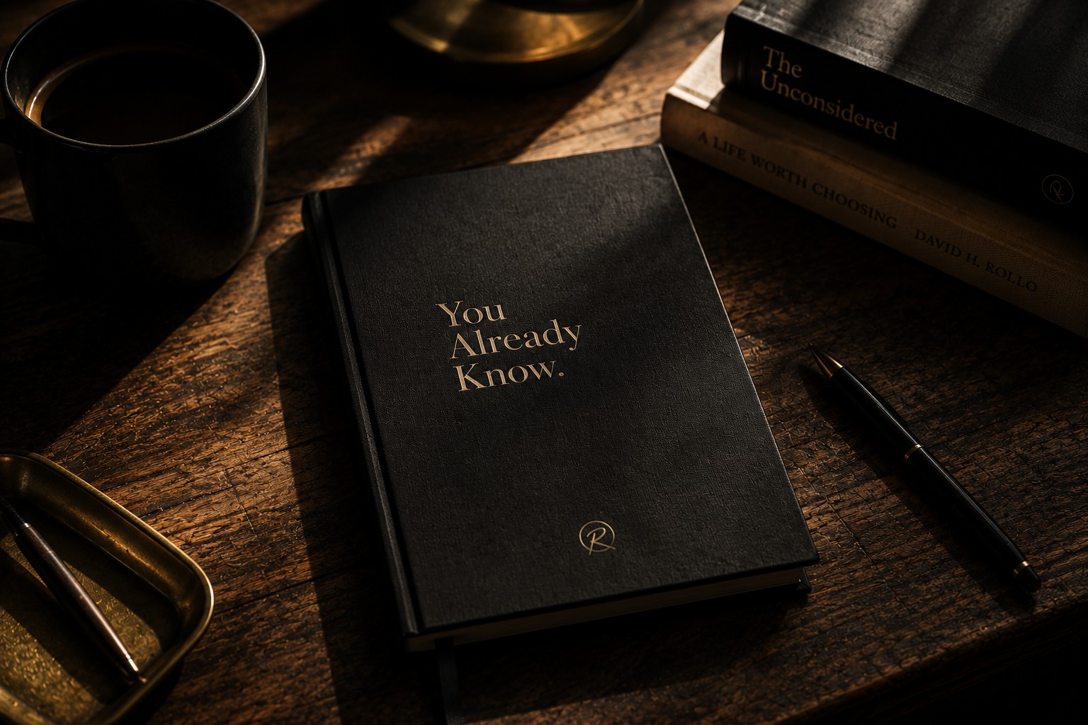 The Questions Journal, a debossed linen journal resting on a second copy opened to a workbook page